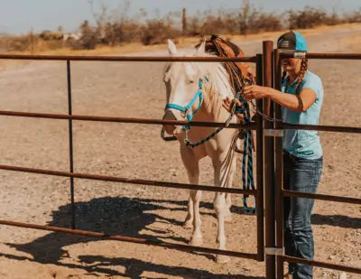 Woman tying a horse to a rail